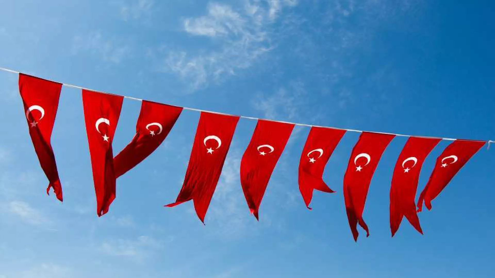Rijen Turkse vlaggen wapperen tegen een blauwe lucht.