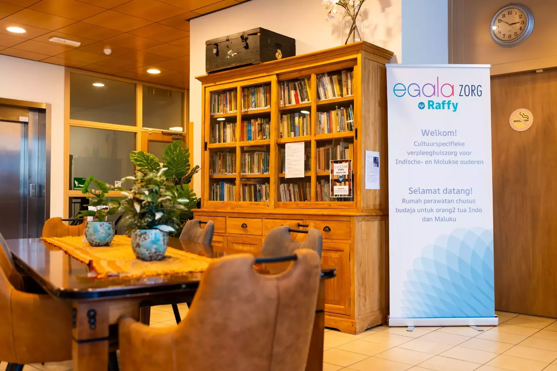 Bibliotheekhoek in een gezellige ruimte met planten en een tafel.